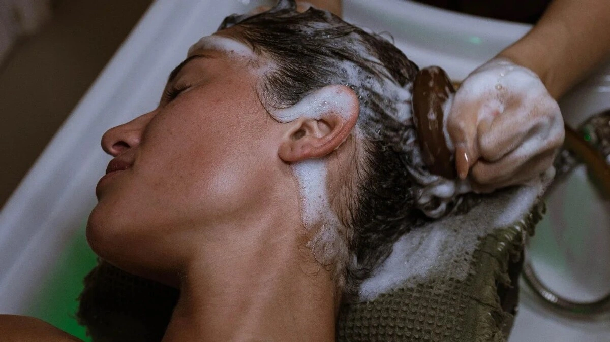 Primo piano di un professionista che esegue un head spa giapponese con una spazzola per il cuoio capelluto su una cliente