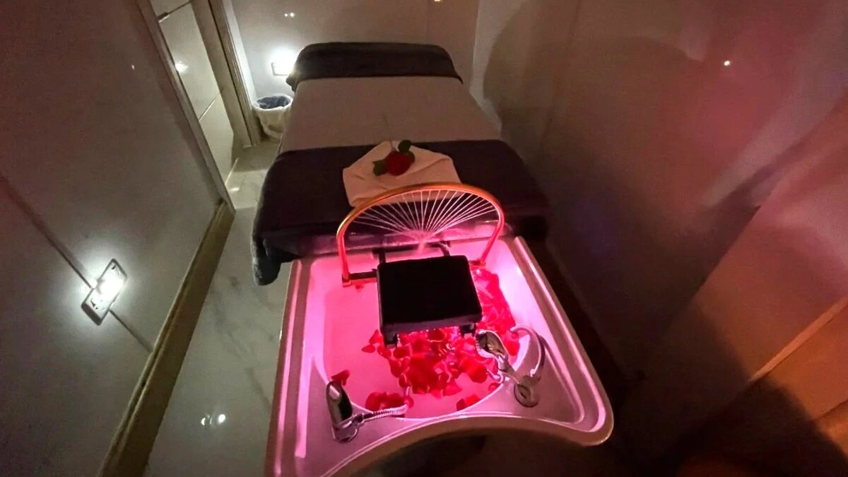 Interno di una sala per head spa giapponese accogliente e con luci soffuse, con un lettino, un lavatesta con petali e attrezzature da spa