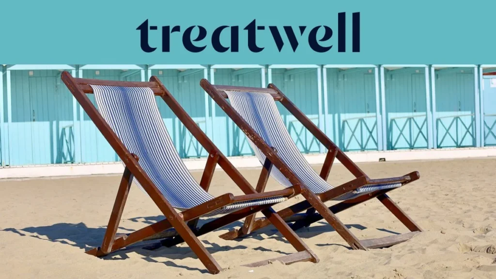 Due sdraio in legno a righe sulla sabbia davanti alle cabine di un bagno color azzurro pastello in Versilia