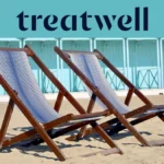 Due sdraio in legno a righe sulla sabbia davanti alle cabine di un bagno color azzurro pastello in Versilia