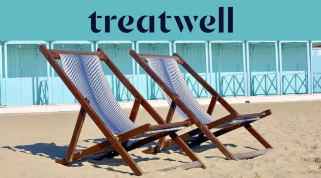 Due sdraio in legno a righe sulla sabbia davanti alle cabine di un bagno color azzurro pastello in Versilia