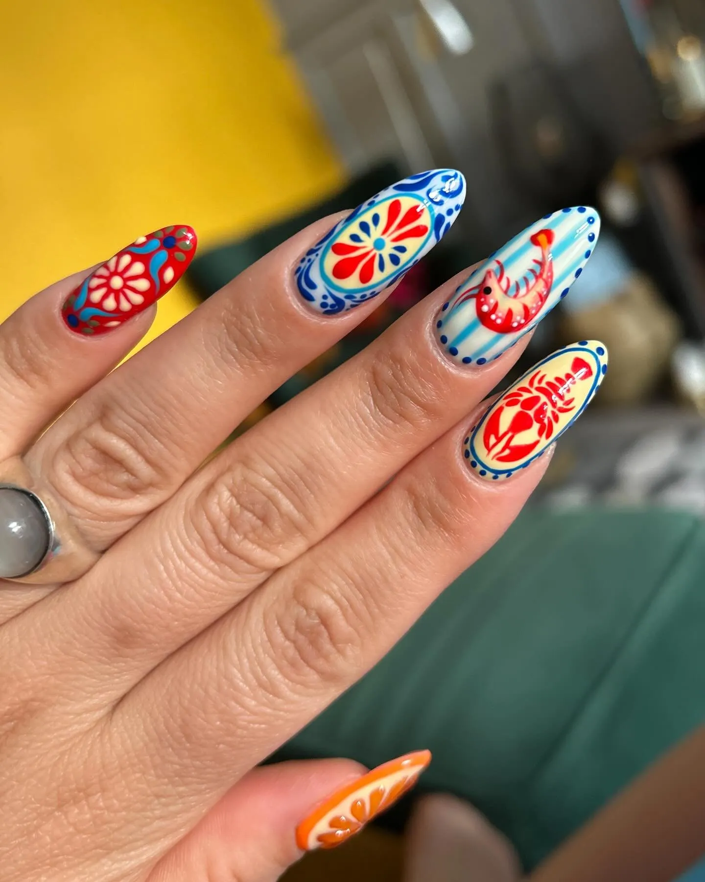 Nail art Destination nails su unghie a mandorla, motivi di ispirazione mediterranea in rosso, blu e arancione