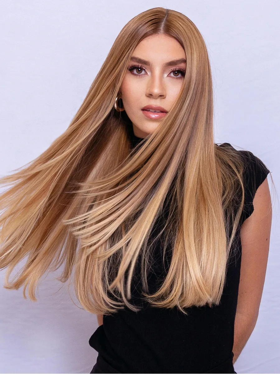 Ritratto in studio di una donna che muove i lunghi capelli biondo caramello e lucidi