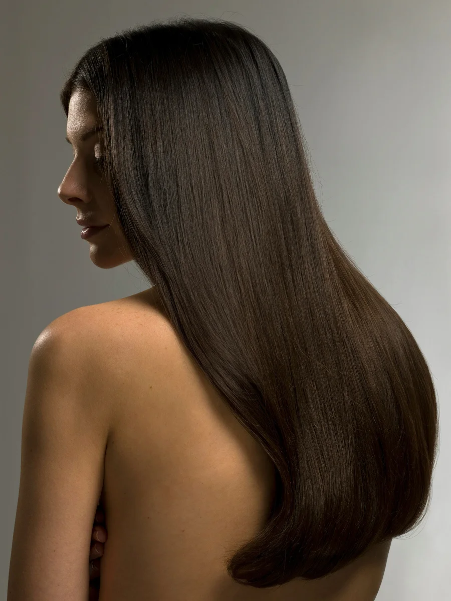 Ritratto in studio di profilo di una donna con lunghi capelli castani e lucidi