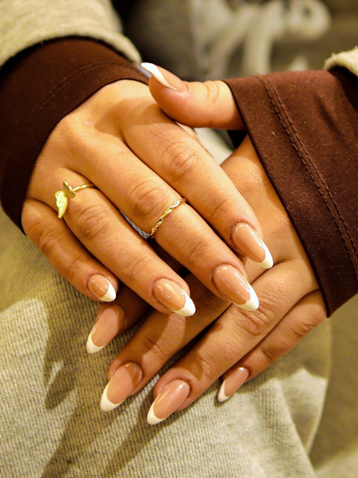 Le mani di una donna con un'audace French manicure in una combinazione di beige e bianco su unghie lunghe a mandorla
