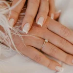 French manicure classica bianca su unghie naturali dalla forma squadrata, su un tessuto bianco