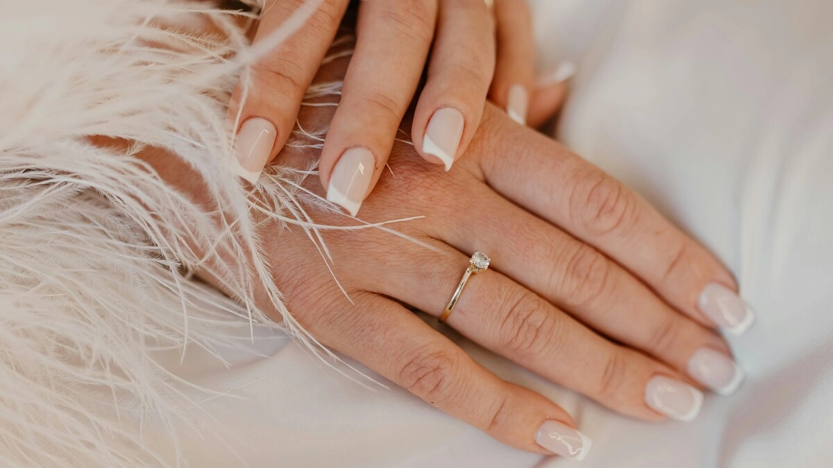French manicure classica bianca su unghie naturali dalla forma squadrata, su un tessuto bianco