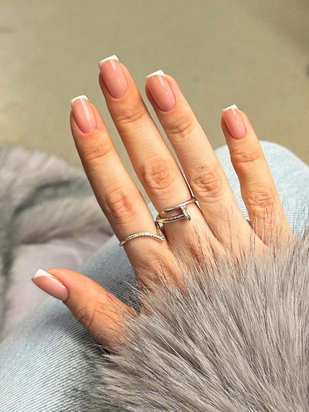La mano di una donna con una French manicure con micro-linee su unghie squadrate