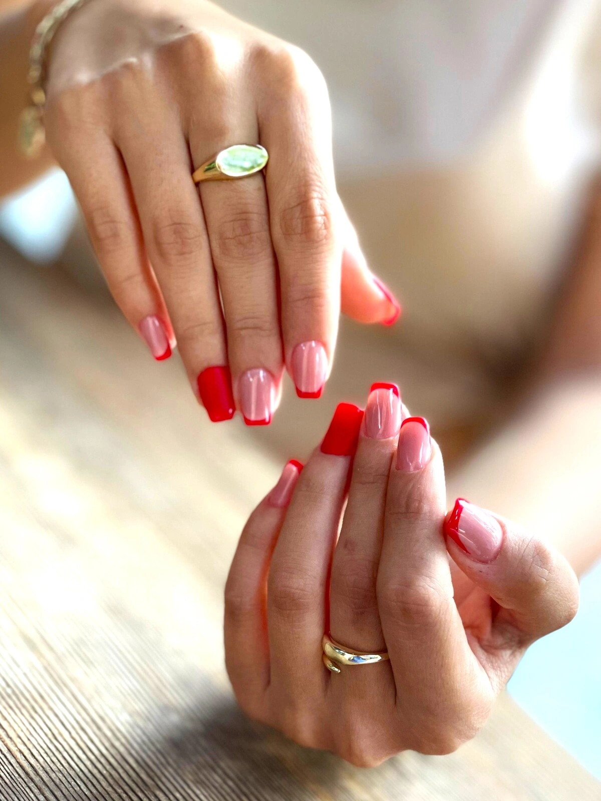 Una French manicure su unghie squadrate-ovali con base rosa chiaro e punte rosse, e anulari completamente rossi