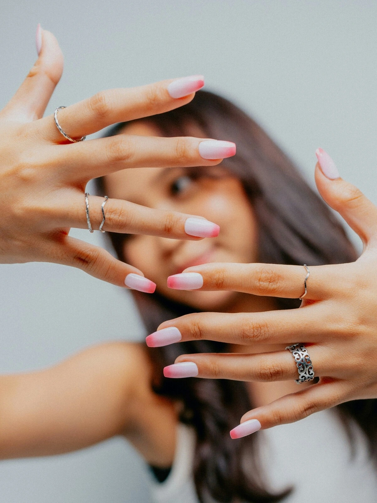 Una donna mostra le mani verso l'obiettivo con una French manicure in versione ombré, dalla base rosa chiaro e punte rosa acceso su unghie a ballerina