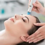 Primo piano di una donna rilassata con gli occhi chiusi durante un trattamento HydraFacial in un salone tranquillo