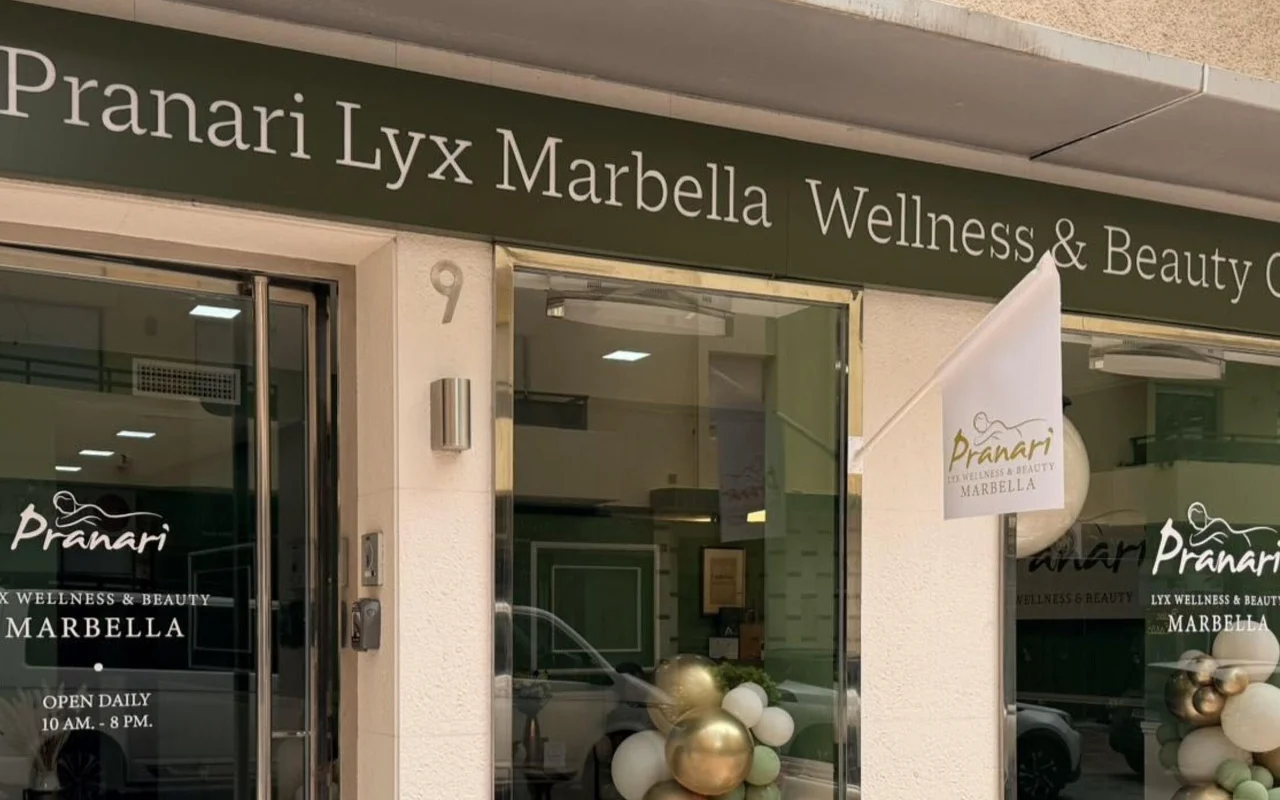 La sede di Anchan Massage a Marbella, uno studio di benessere e bellezza dalla facciata verde, con palloncini bianchi e dorati accanto all'ingresso a vetri.