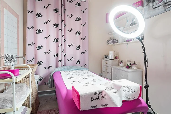 Cabina rosa al Centro Estetico Karma a Olbia con tende con stampa di ciglia, lettino da estetica e luce ad anello.