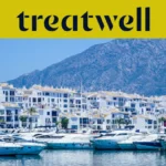 Il porto turistico di Puerto Banús, a Marbella, circondato da edifici bianchi e yacht ormeggiati sullo sfondo delle montagne, sotto uno striscione giallo Treatwell.