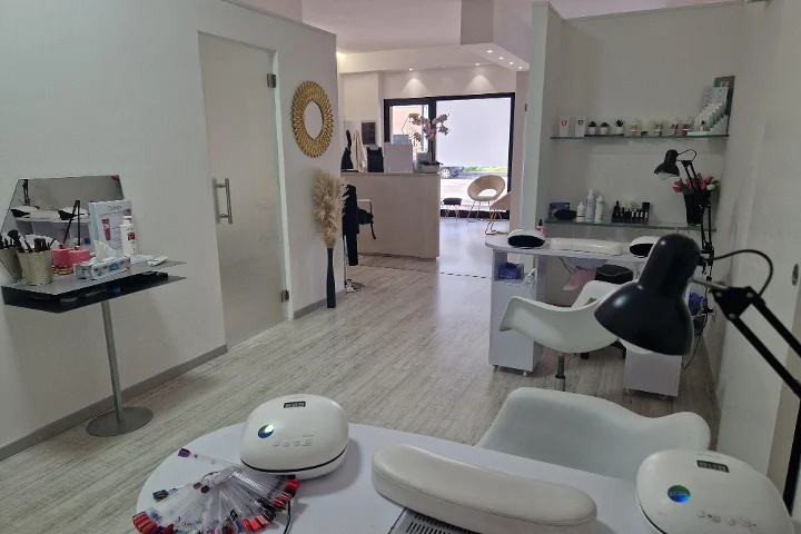 Reception e area manicure da Estetica Francesca a Olbia con specchio rotondo alla parete e mensole in vetro con prodotti beauty.