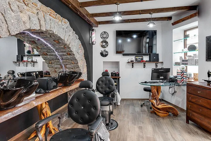 Poltrona da barbiere rustica davanti a un arco in pietra da La Bottega di Pablo, nel paese di montagna di Lanusei.