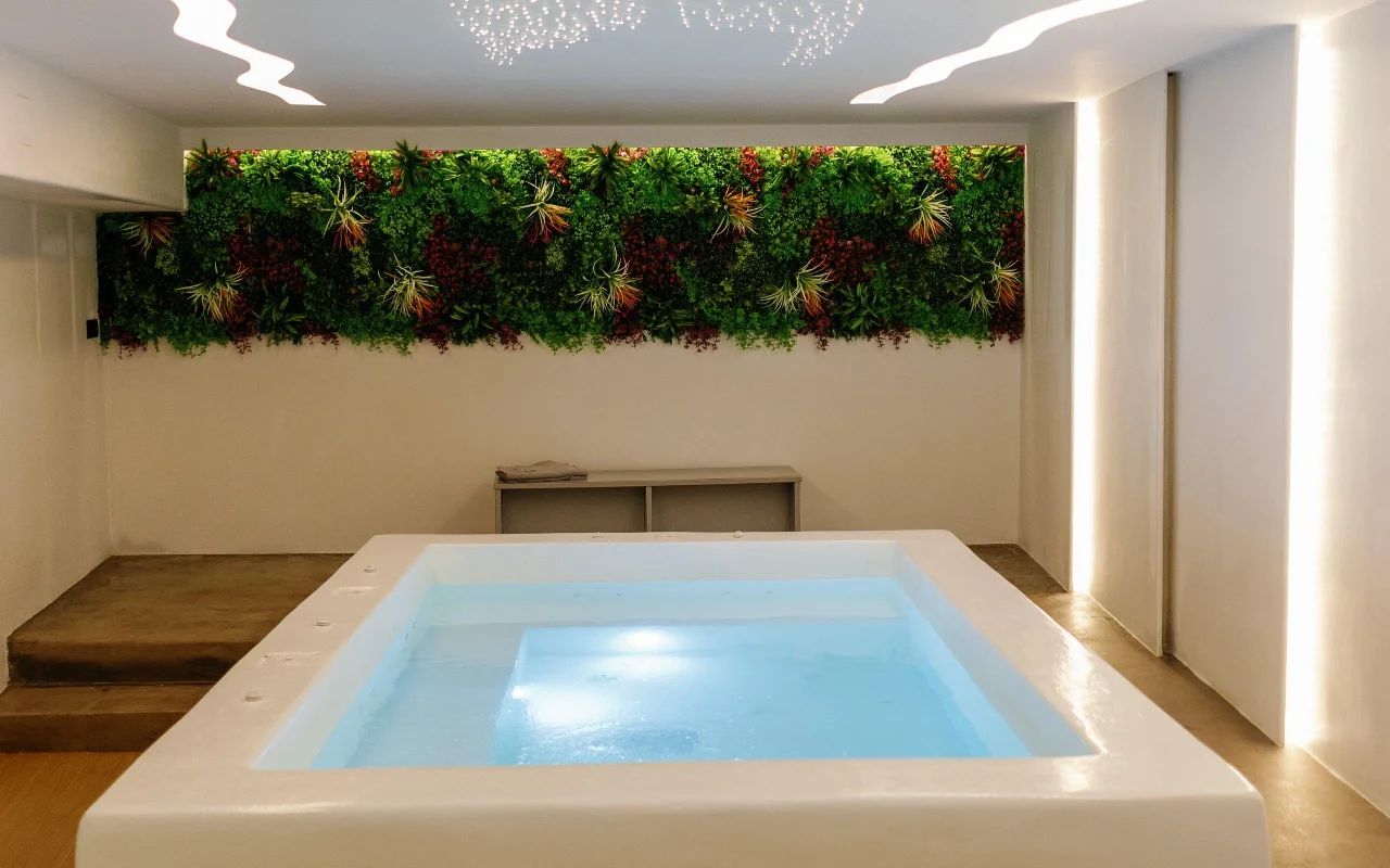 La piscina idroterapica di Liana Spa Therapy a Naxos, illuminata dolcemente dall'interno, sotto una parete verde colorata di piante stabilizzate e un soffitto punteggiato di minuscole stelle luminose.