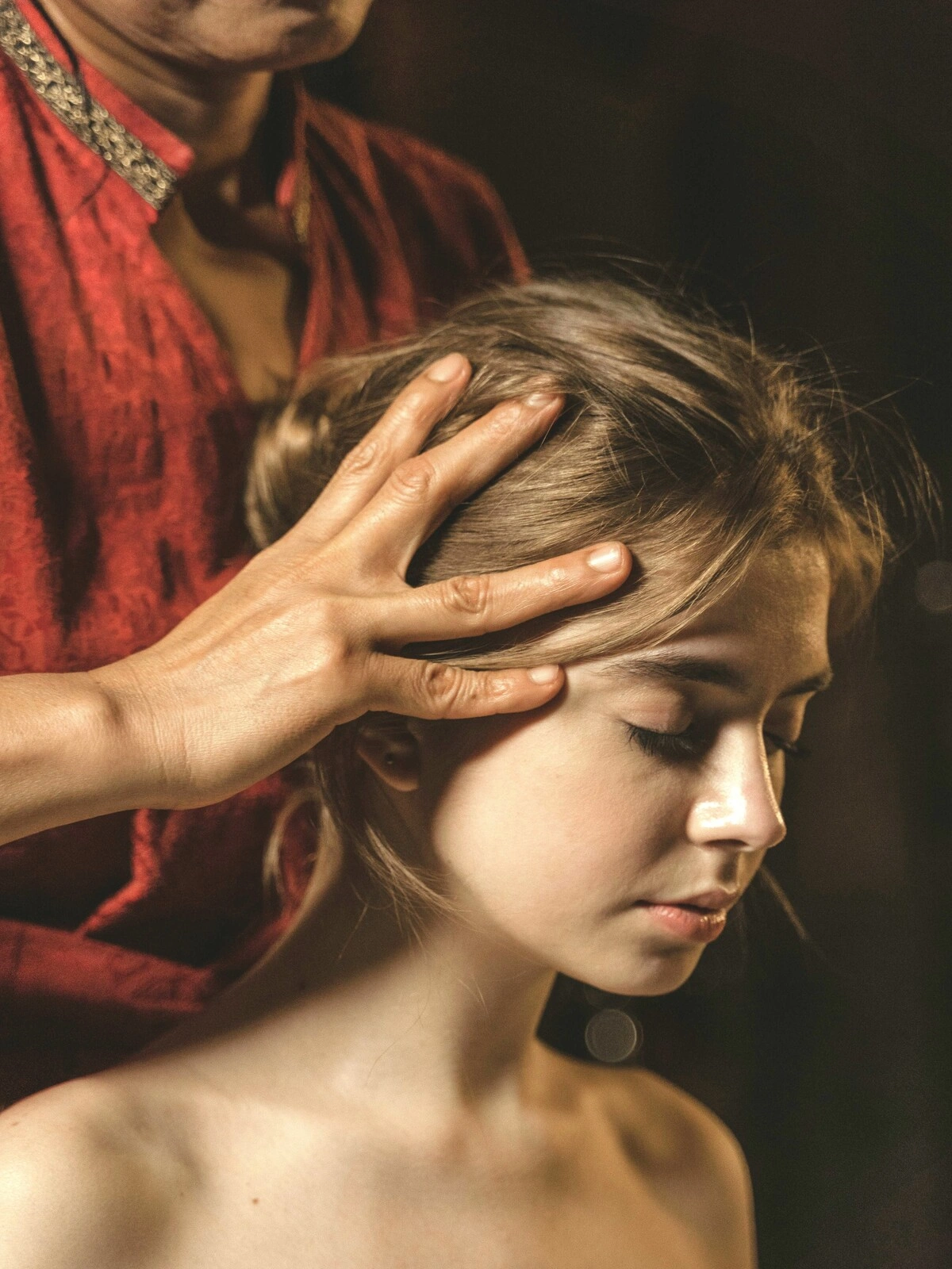 Primo piano di una donna con gli occhi chiusi mentre una professionista le massaggia il cuoio capelluto durante un massaggio indiano della testa